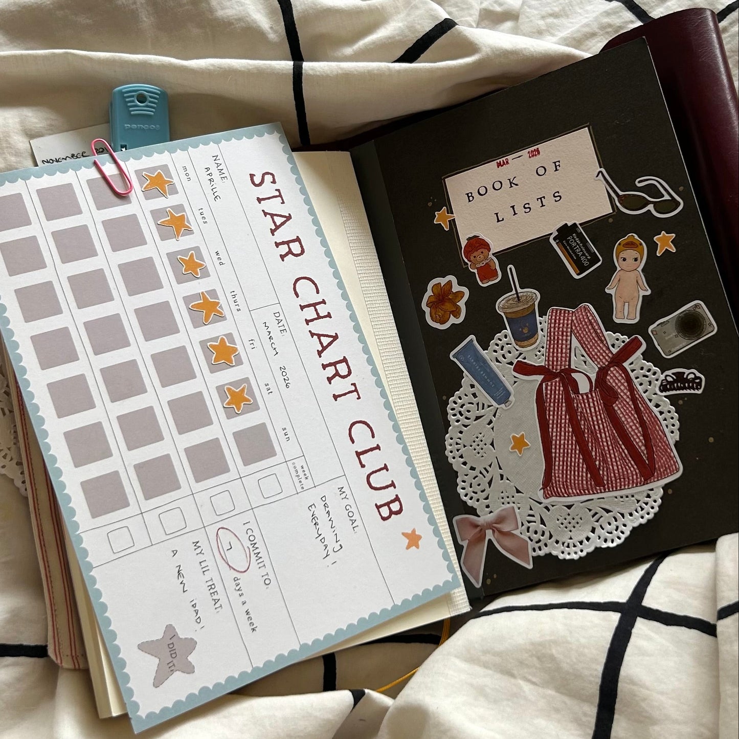 star chart club clipped to the inside of a journal next to a notebook that says book of lists.