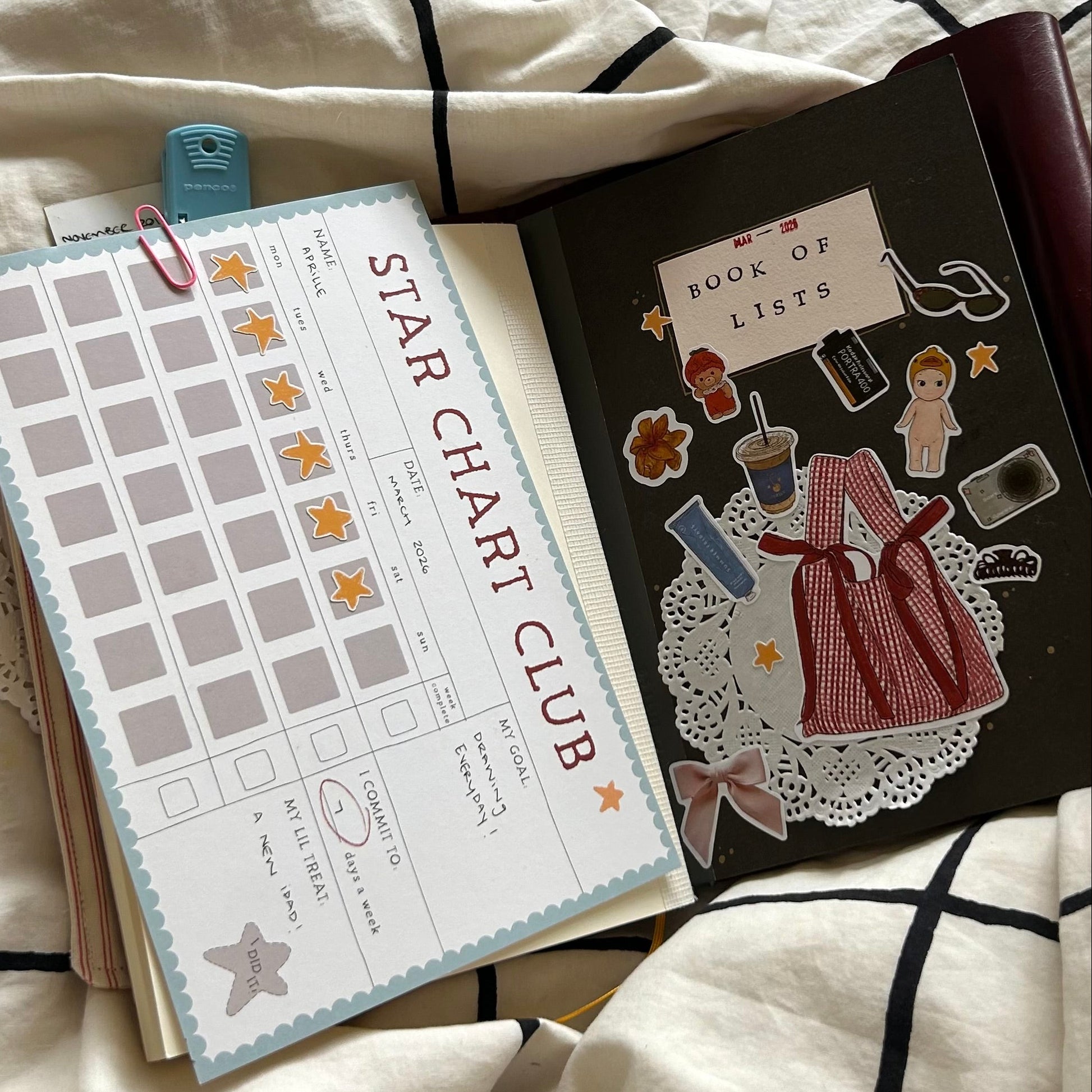 star chart club clipped to the inside of a journal next to a notebook that says book of lists.